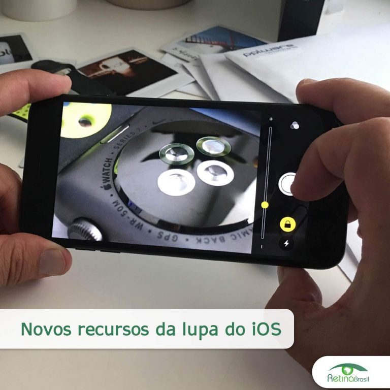#DescriçãoDaImagem: Imagem Ilustrativa. Aparece na imagem duas mãos segurando um smartphone com o recurso da lupa ativado. Na tela do celular é possível ver a imagem aproximada do que está em cima de uma mesa. O título da imagem é "Novos recursos da lupa do iOS" e a logo da Retina Brasil está no canto inferior direito.